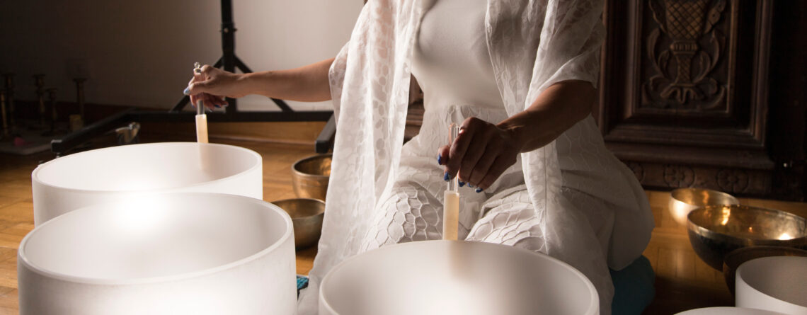 Woman In Sound Healing Therapy Using Crystal Singing Bowls